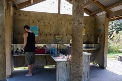 Homem em abrigo para cozinhar em camping na Nova Zelândia
