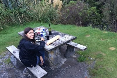Mulher faz lanche em mesa de camping na Nova Zelândia