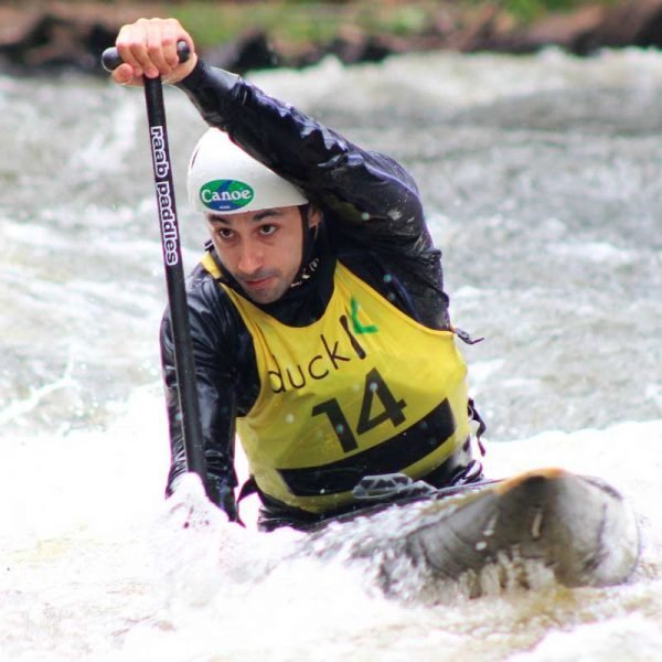 Atleta rema em canoa individual em competição de slalom