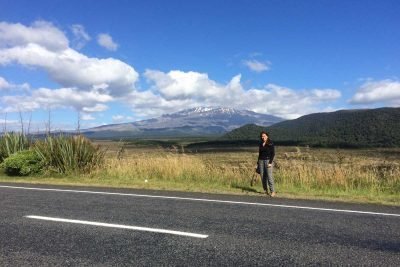 Mulher em frente a uma paisagem de campo e montanhas na Nova Zelândia