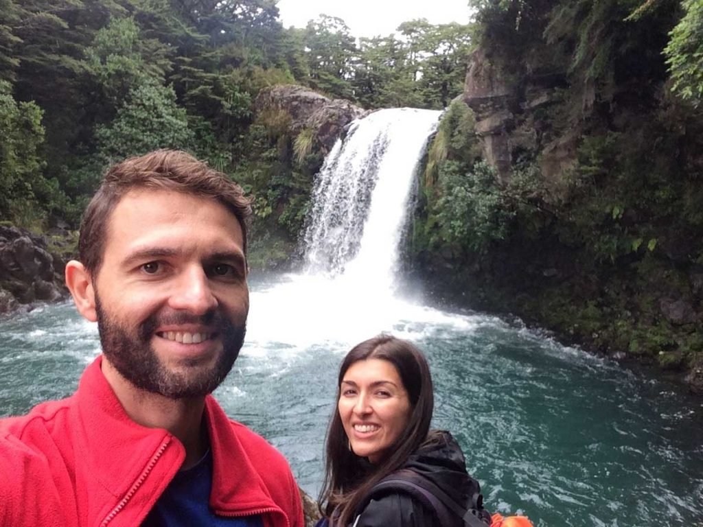 Casal em frente a cachoeira no parque nacional de Tongariro