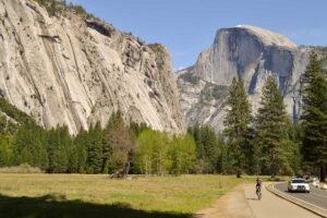 Yosemite-Valley Foto mostra a estrada que corta o vale de Yosemite e os paredões de pedra ao redor, com Half Dome em destaque